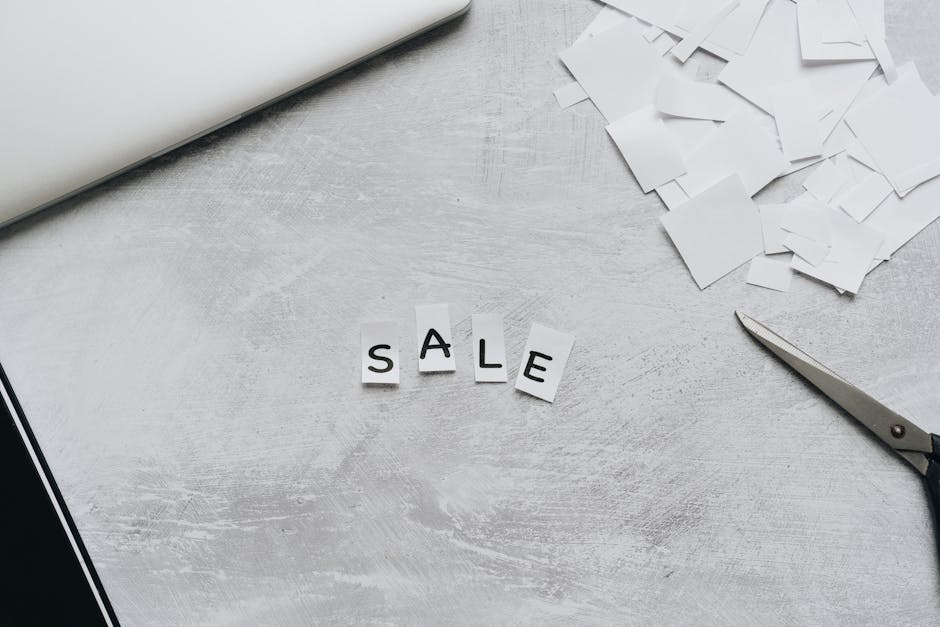 Overhead view of cut-out letters spelling 'Sale' on a desk with scattered paper and scissors.