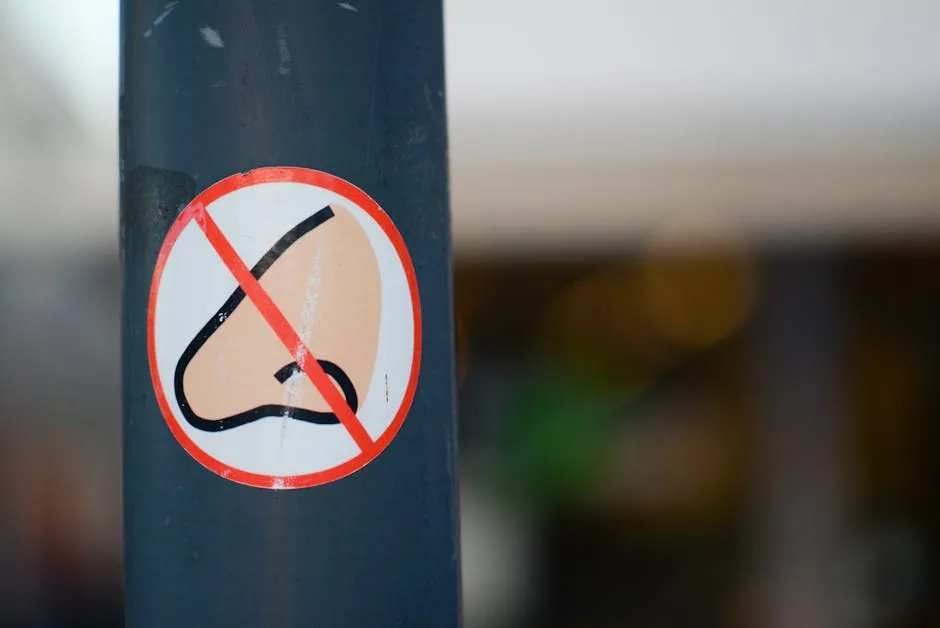 A close-up of a warning sticker depicting a nose with a prohibition sign on a metal post.